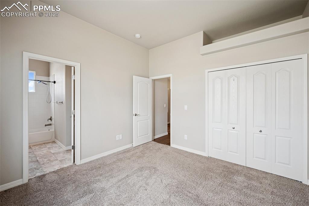Image 15 of 38: Unfurnished bedroom featuring carpet floors, baseboards, ensuite bath, and