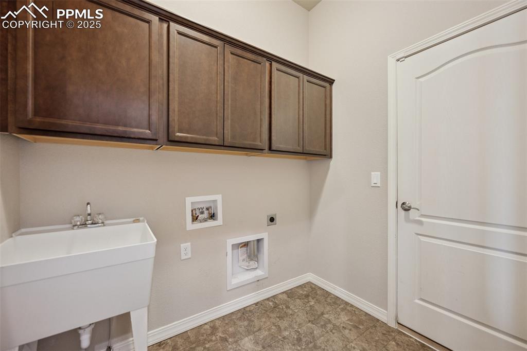 Image 18 of 38: Clothes washing area featuring hookup for an electric dryer, cabinet space,