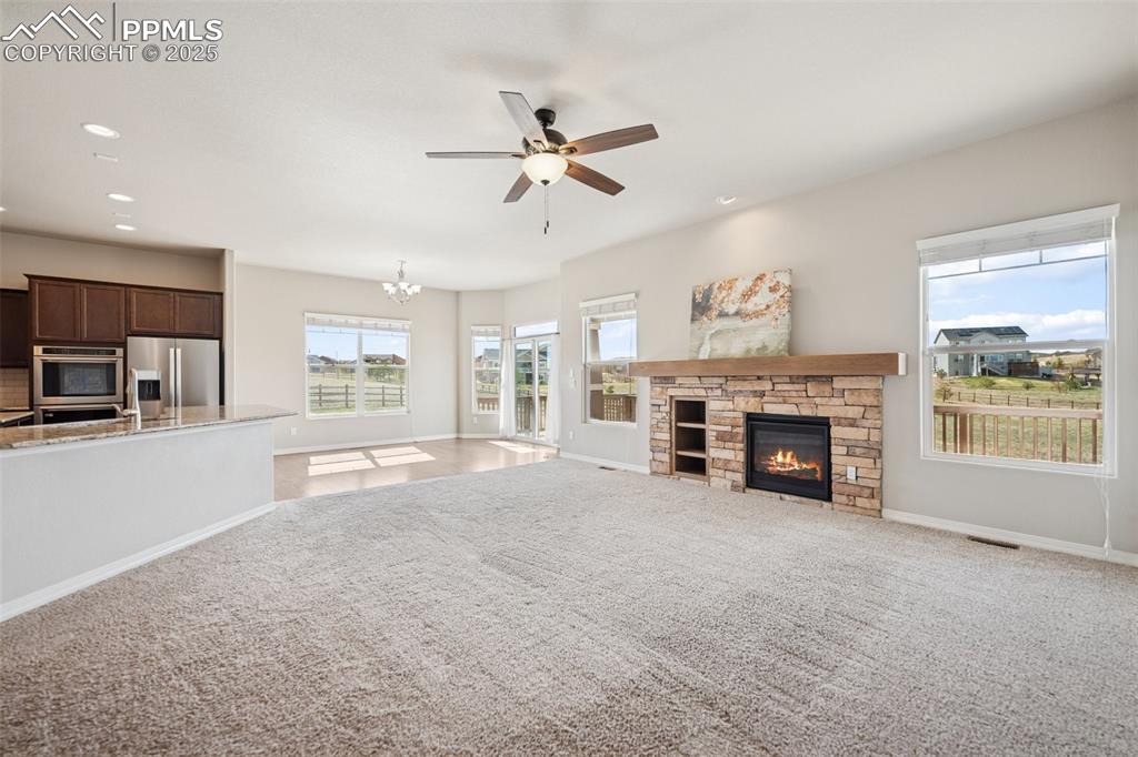 Image 2 of 38: Unfurnished living room featuring carpet, baseboards, a fireplace, and ceil