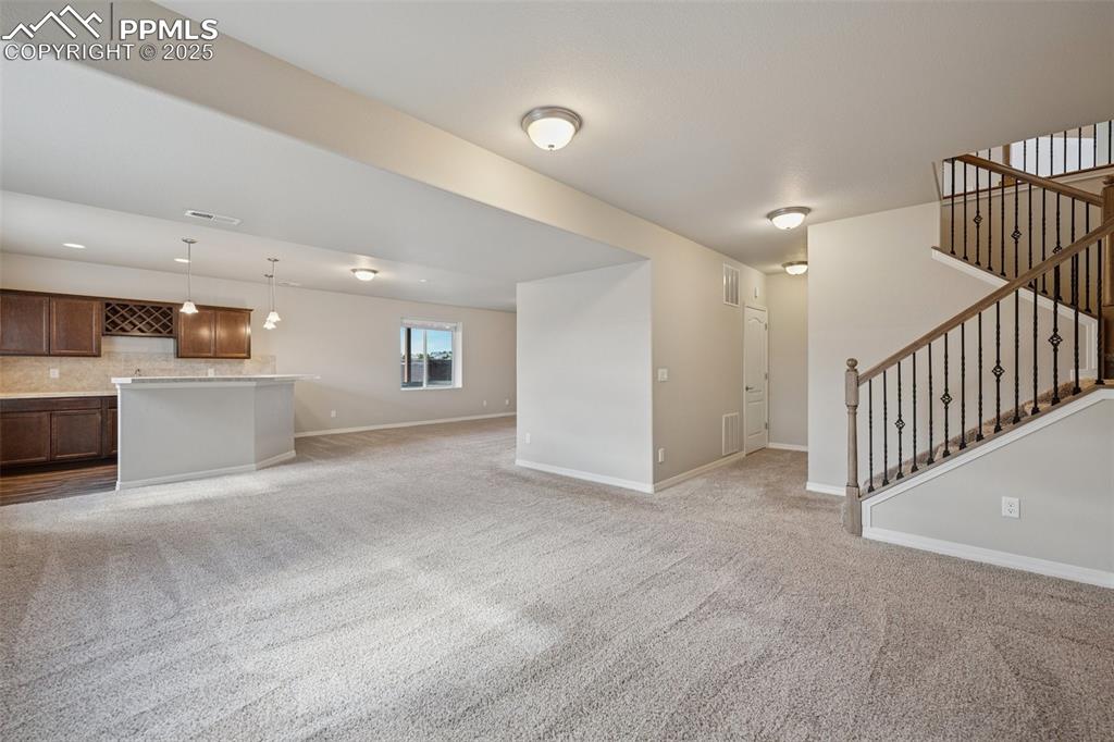 Image 21 of 38: Unfurnished living room featuring visible vents, baseboards, light colored