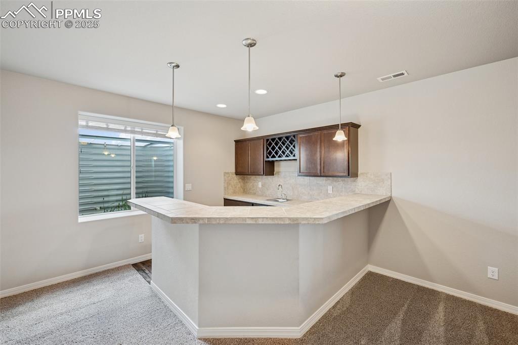 Image 23 of 38: Kitchen featuring dark brown cabinets, a sink, light countertops, tasteful