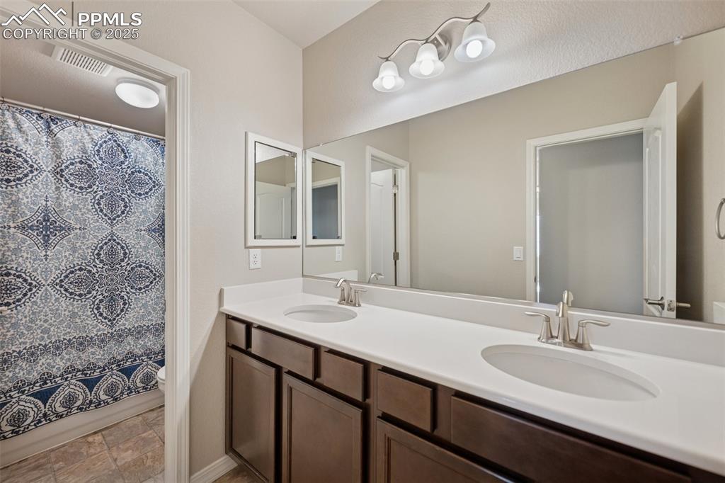 Image 27 of 38: Bathroom featuring double vanity, a sink, a shower with shower curtain, and