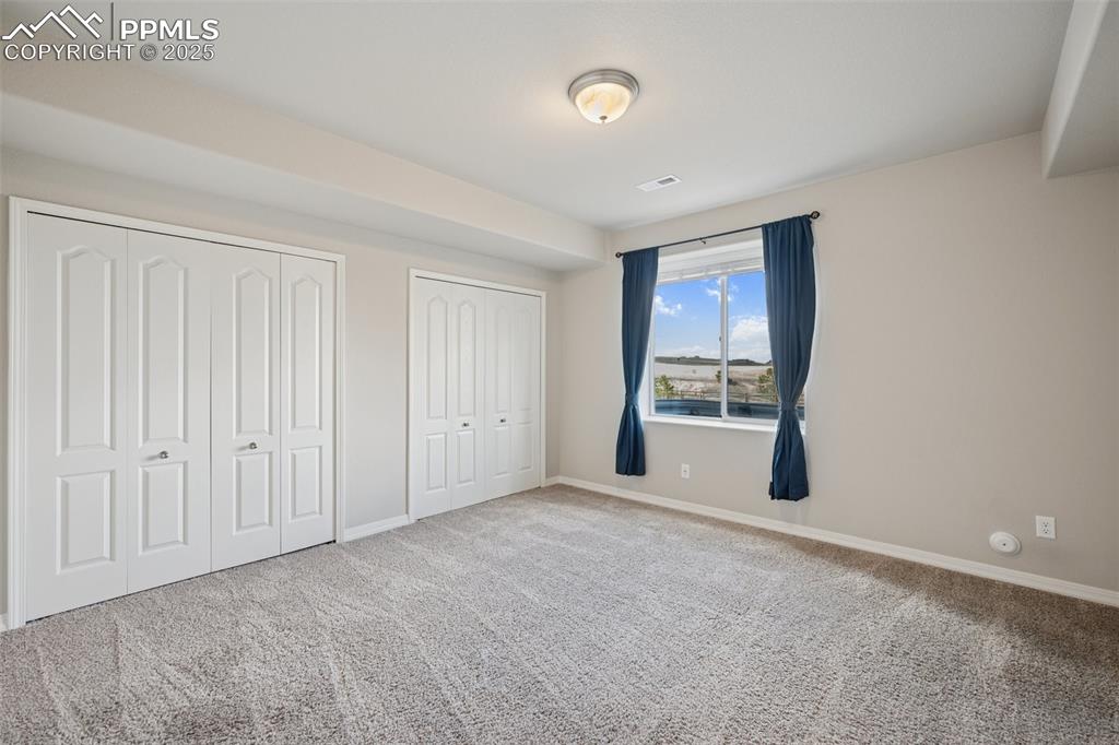 Image 28 of 38: Unfurnished bedroom featuring baseboards, carpet, two closets, and visible
