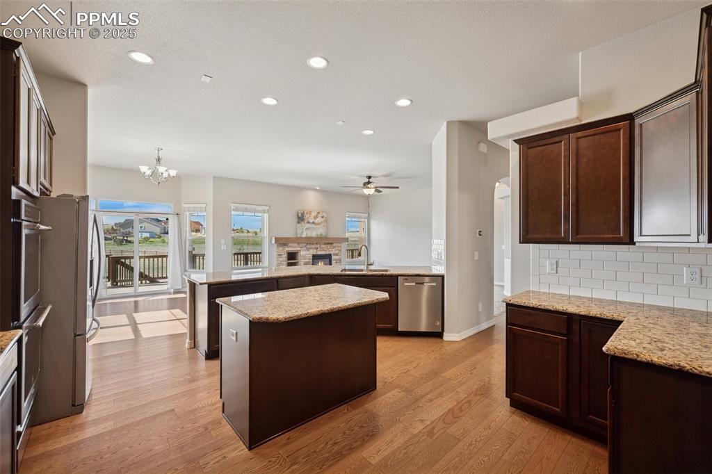 Image 3 of 38: Kitchen with a sink, ceiling fan with notable chandelier, stainless steel a