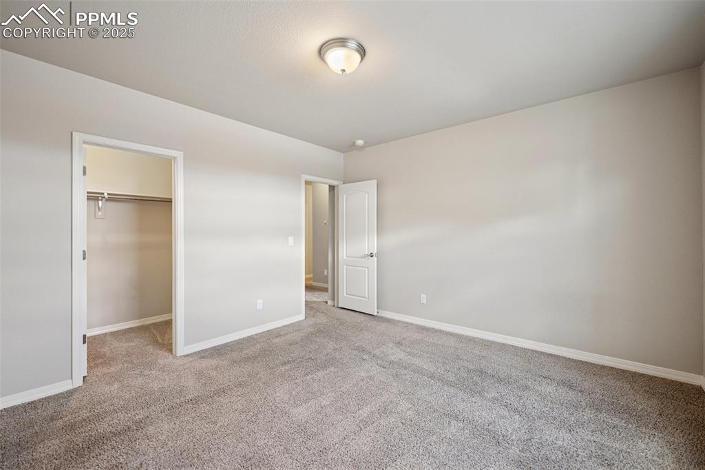 Image 31 of 38: Unfurnished bedroom with carpet floors, baseboards, a walk in closet, and a