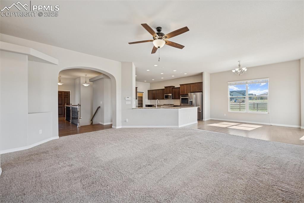Image 6 of 38: Unfurnished living room featuring arched walkways, a sink, baseboards, ceil