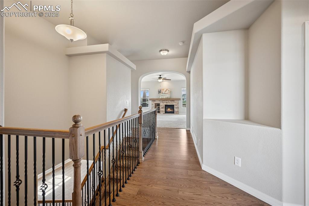 Image 7 of 38: Hall featuring arched walkways, baseboards, wood finished floors, and an up