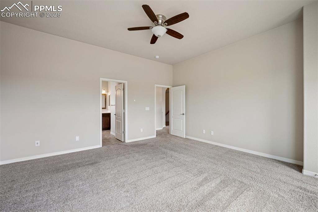 Image 9 of 38: Unfurnished bedroom with carpet floors, baseboards, ceiling fan, and ensuit