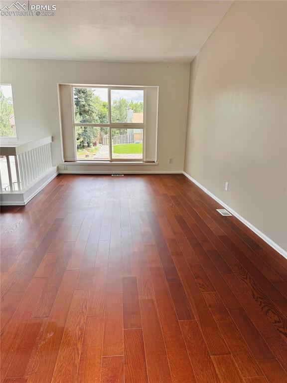 Image 2 of 11: Spare room featuring dark wood-style floors and plenty of natural light