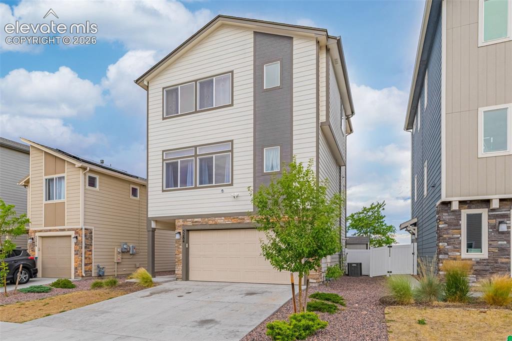 Image 1 of 46: Modern three-story residence featuring light siding with dark grey accents 