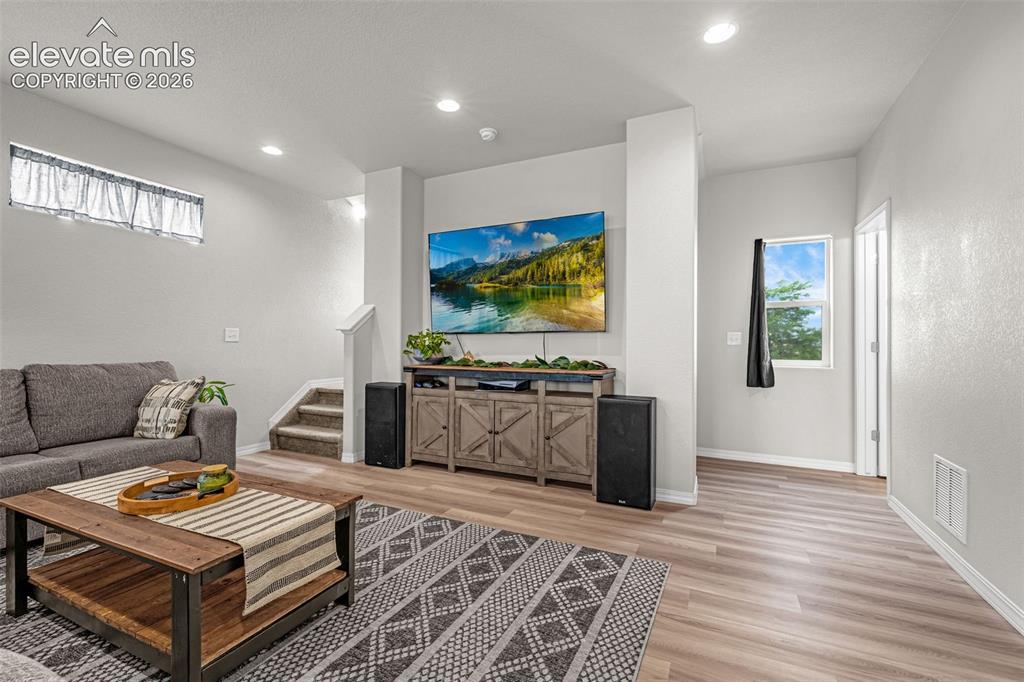 Image 20 of 46: Spacious living area featuring light wood-finish flooring, recessed lightin