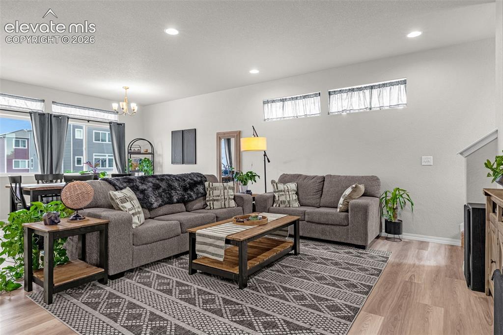 Image 23 of 46: Open-concept living area with light wood-finish flooring, recessed lighting