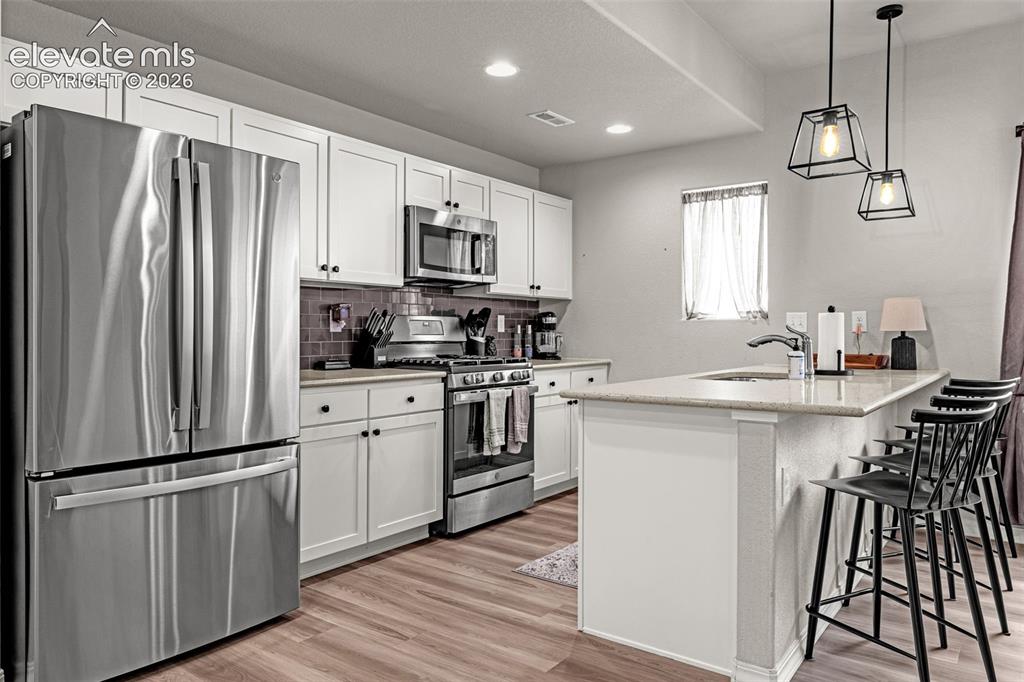 Image 24 of 46: Kitchen featuring stainless steel appliances, white cabinetry, wood-finish 