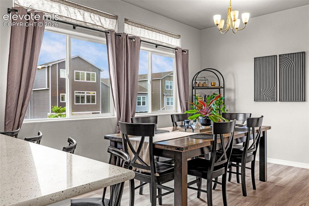 Image 26 of 46: Bright dining area featuring a gold chandelier, light gray walls, and wood-