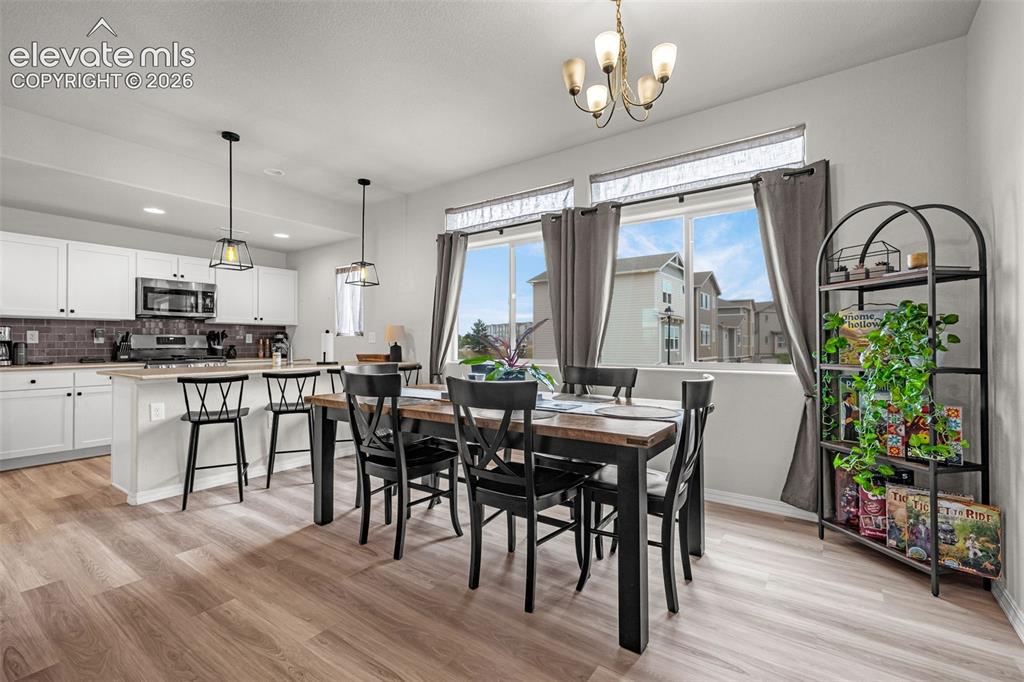 Image 27 of 46: Open-concept kitchen and dining area featuring white cabinetry, a kitchen i