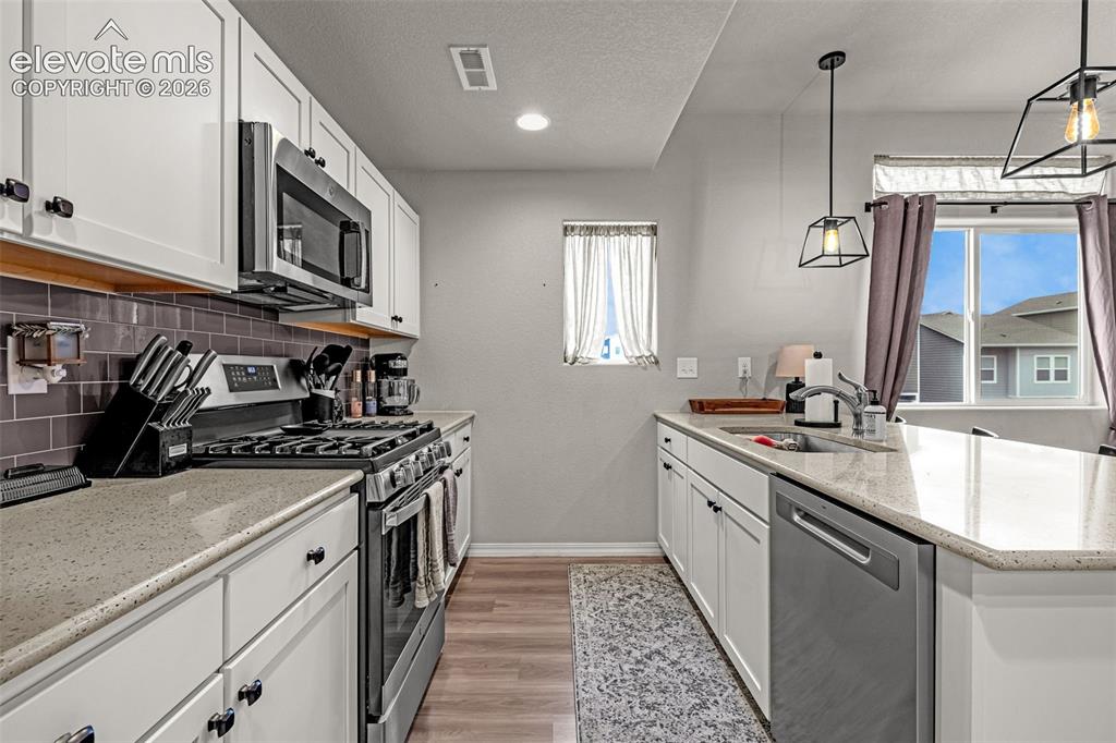 Image 28 of 46: Modern kitchen featuring white cabinetry, light-toned countertops, stainles