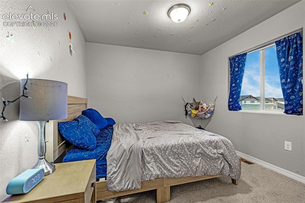 Image 32 of 46: Carpeted room featuring a double-pane window with blue curtains, a wooden b