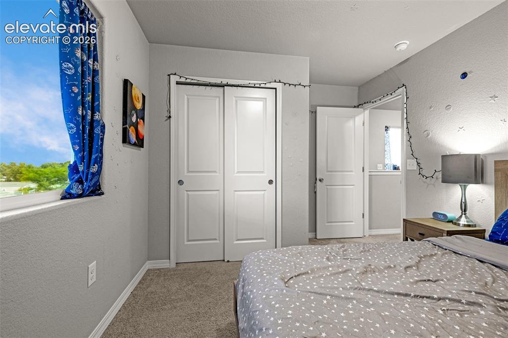 Image 33 of 46: Bedroom featuring a double-pane window, bi-fold closet doors, textured wall