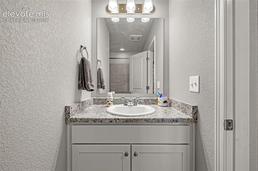 Image 35 of 46: Bathroom vanity featuring a granite-style countertop, undermount sink, and 