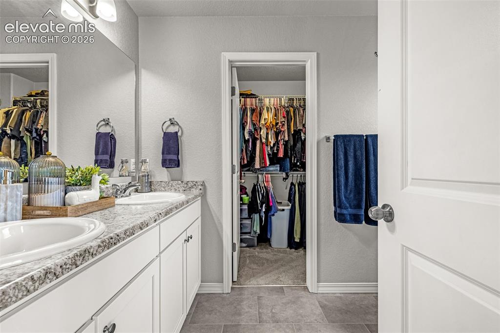 Image 40 of 46: Bathroom featuring a dual vanity with undermount sinks, speckled countertop