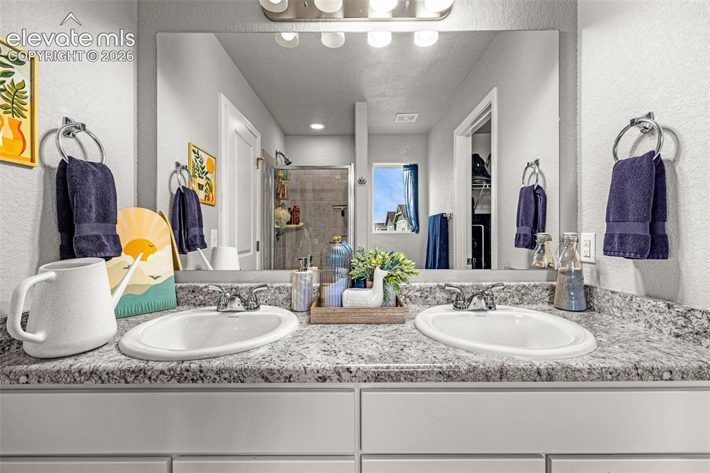 Image 41 of 46: Dual vanity featuring white integrated sinks, speckled countertops, and chr