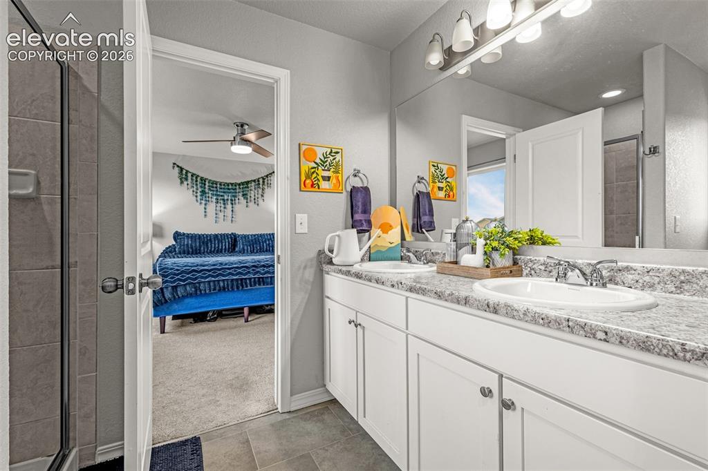 Image 42 of 46: Double vanity with white cabinetry, speckled countertop, and chrome fixture