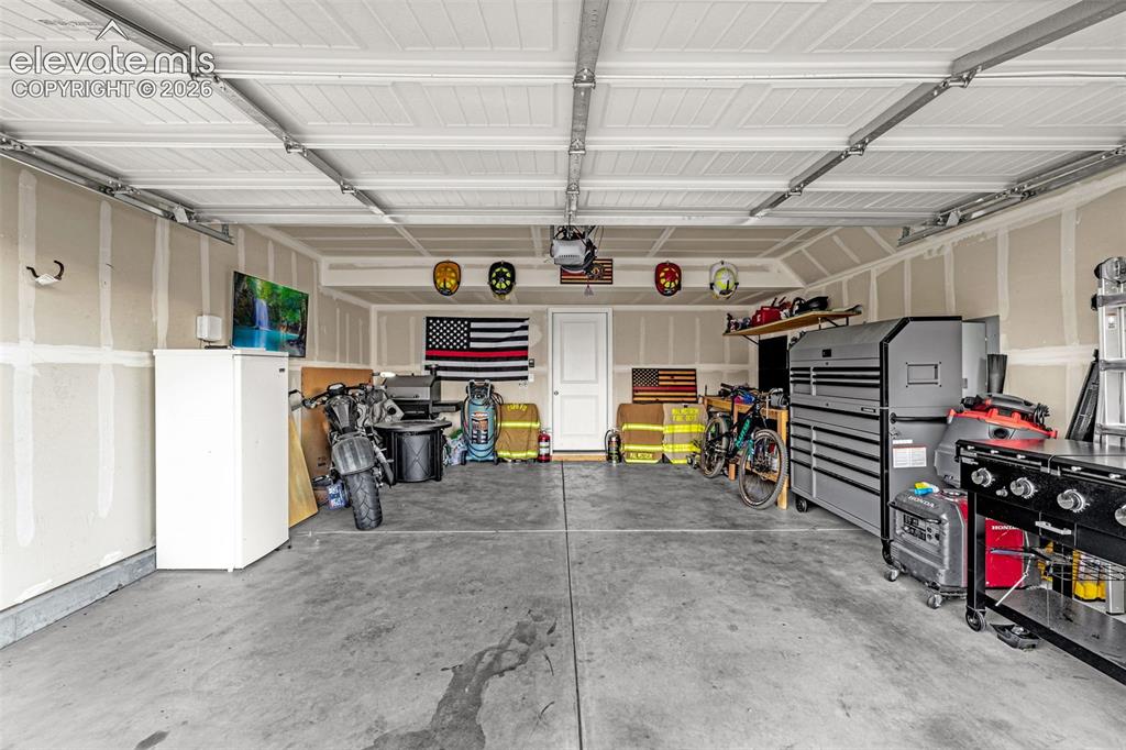 Image 43 of 46: Spacious two-car garage with concrete flooring, finished walls, and white p