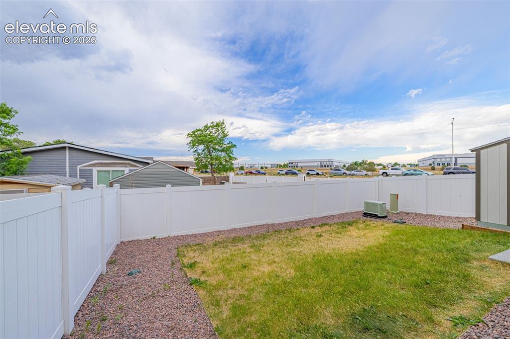 Image 45 of 46: Private backyard featuring a white privacy fence, a patch of green lawn, an