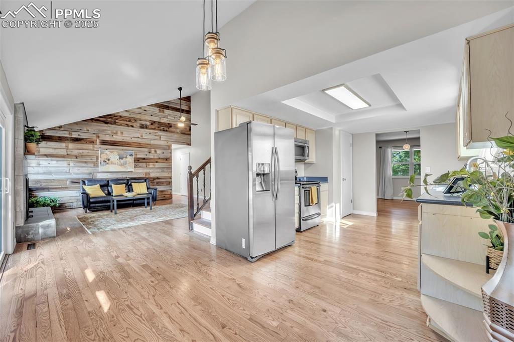 Image 10 of 49: Kitchen featuring wood walls, appliances with stainless steel finishes, lig