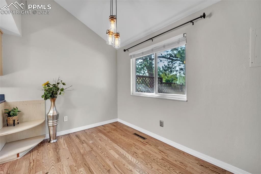Image 11 of 49: Unfurnished dining area featuring light wood-type flooring, lofted ceiling,