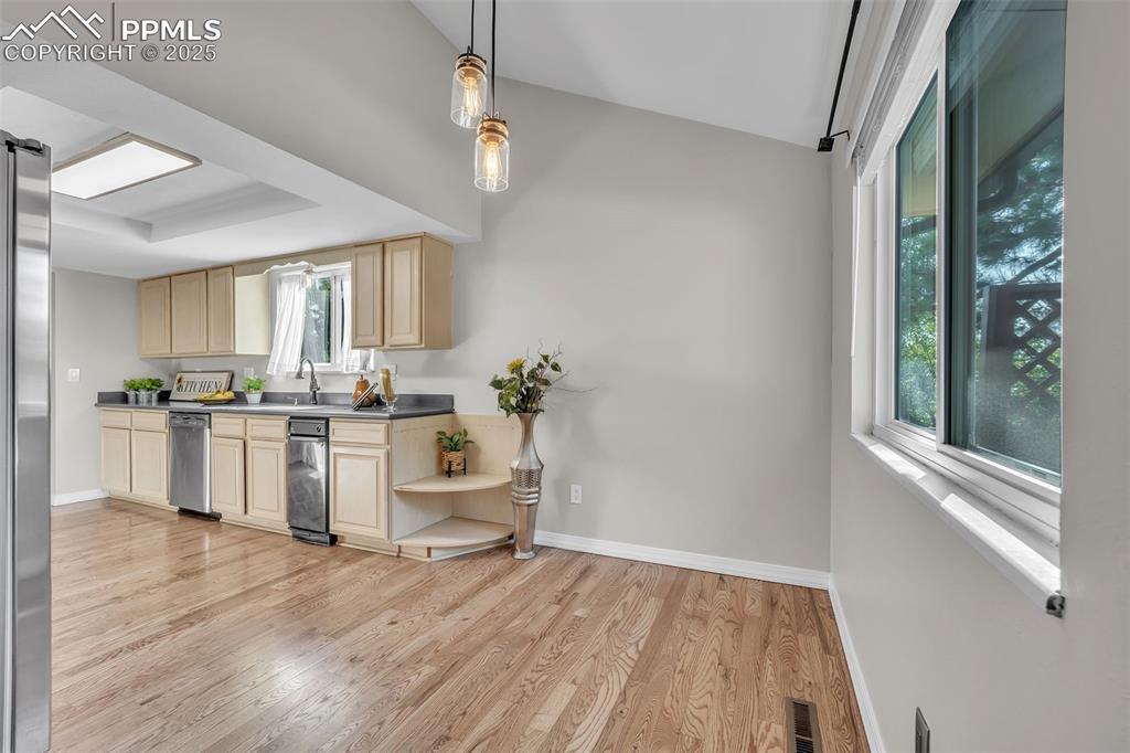 Image 12 of 49: Kitchen with light wood-style floors, decorative light fixtures, appliances