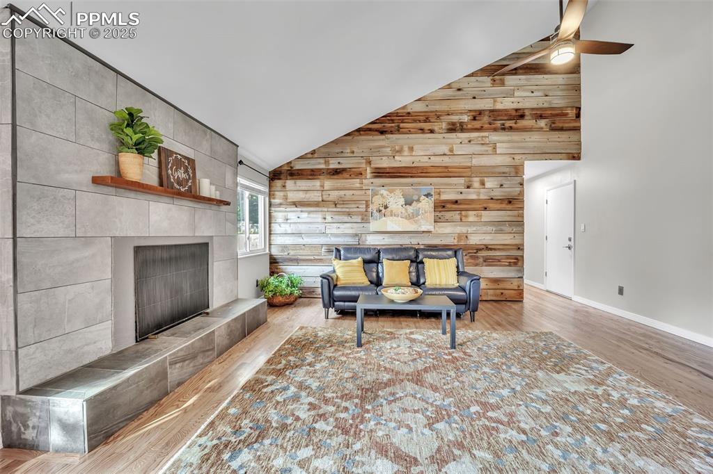 Image 13 of 49: Living area featuring wooden walls, wood finished floors, high vaulted ceil