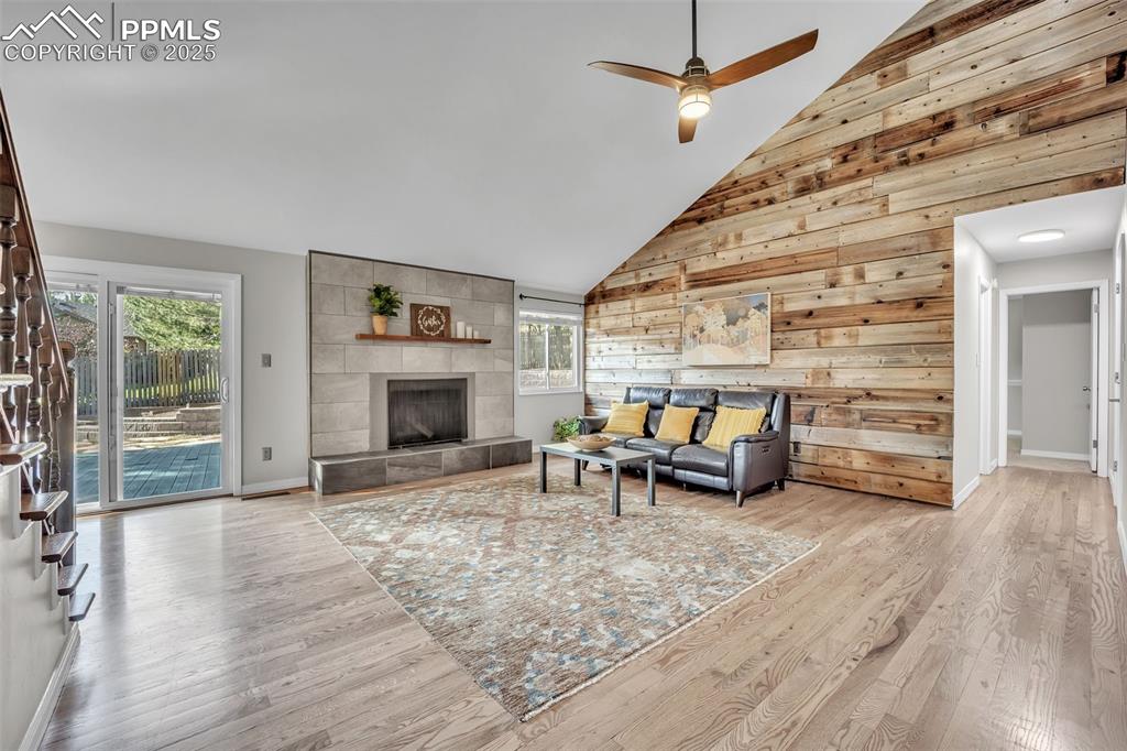 Image 14 of 49: Living area featuring wooden walls, high vaulted ceiling, light wood finish