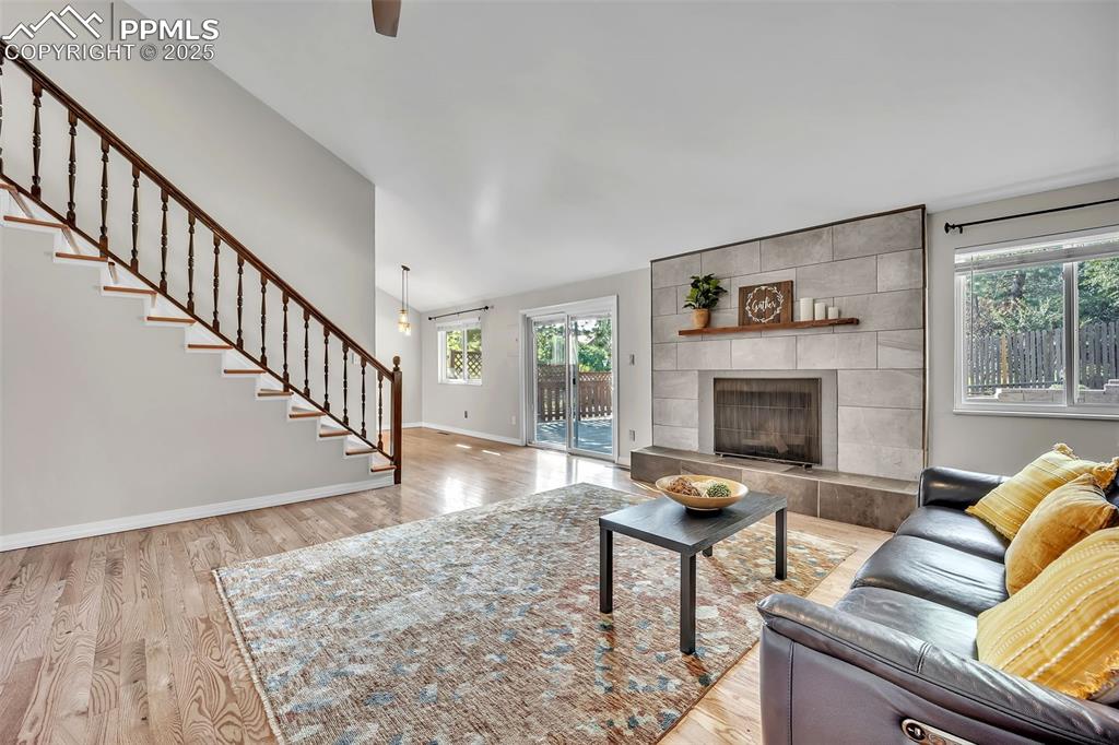 Image 15 of 49: Living area featuring light wood finished floors, stairs, and a tiled firep