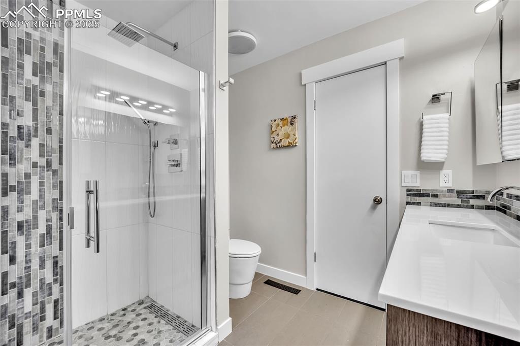 Image 16 of 49: Full bathroom with a stall shower, vanity, and light tile patterned floors
