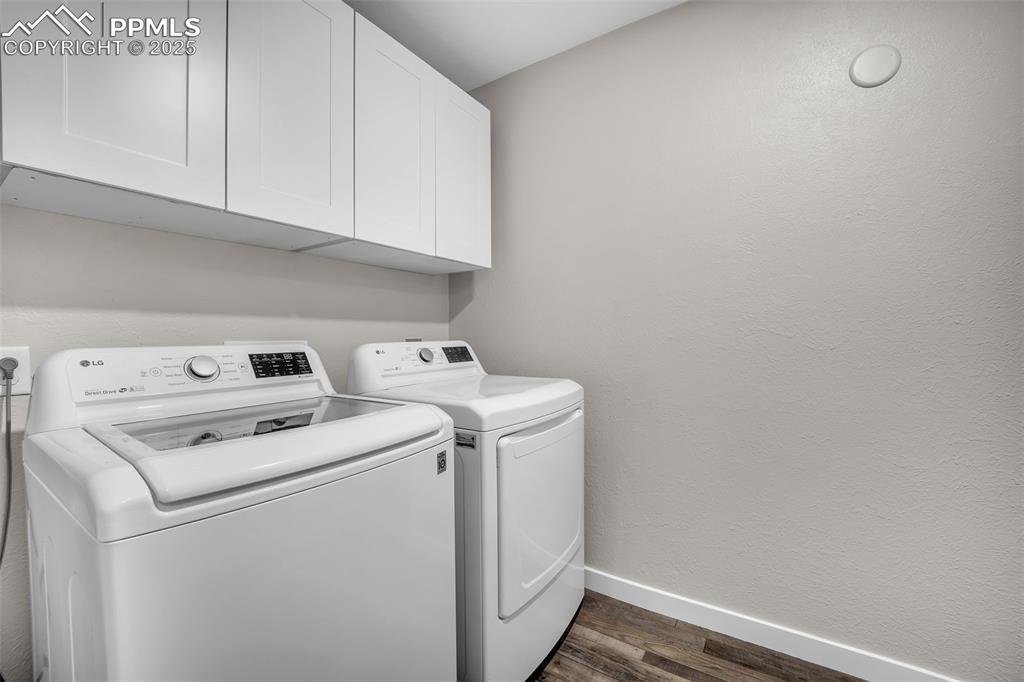 Image 17 of 49: Washroom featuring a textured wall, separate washer and dryer, dark wood-st