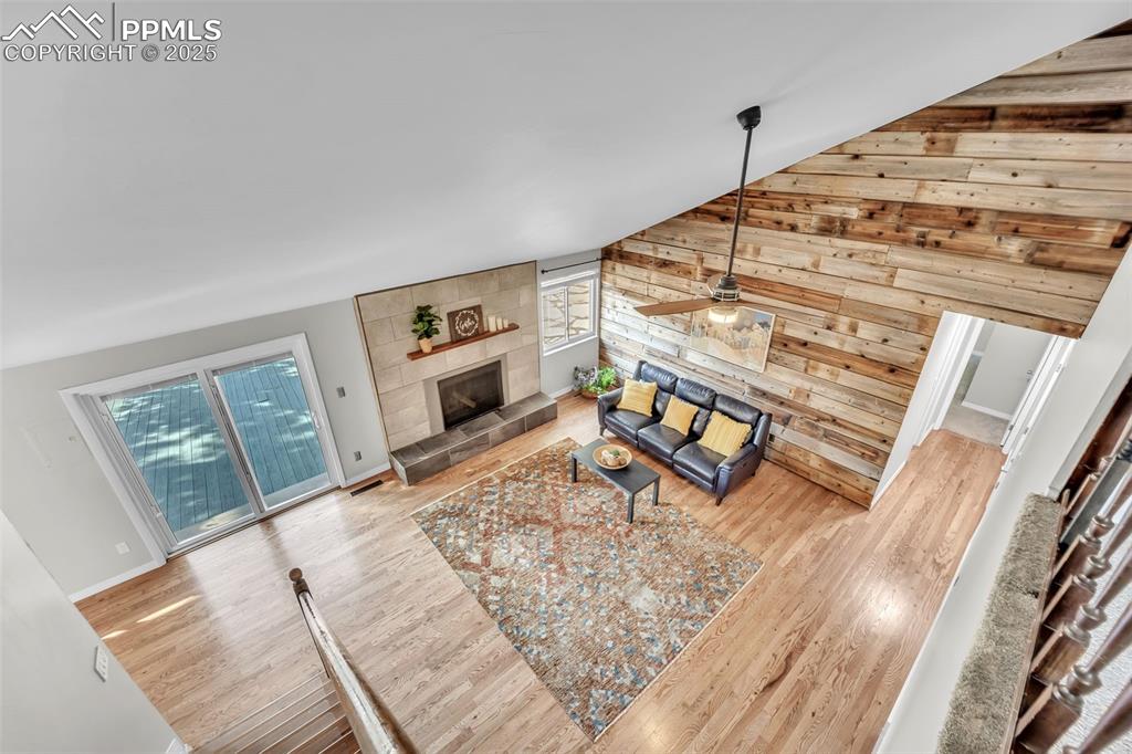 Image 27 of 49: Living room featuring light wood-style floors, wooden walls, a tile firepla