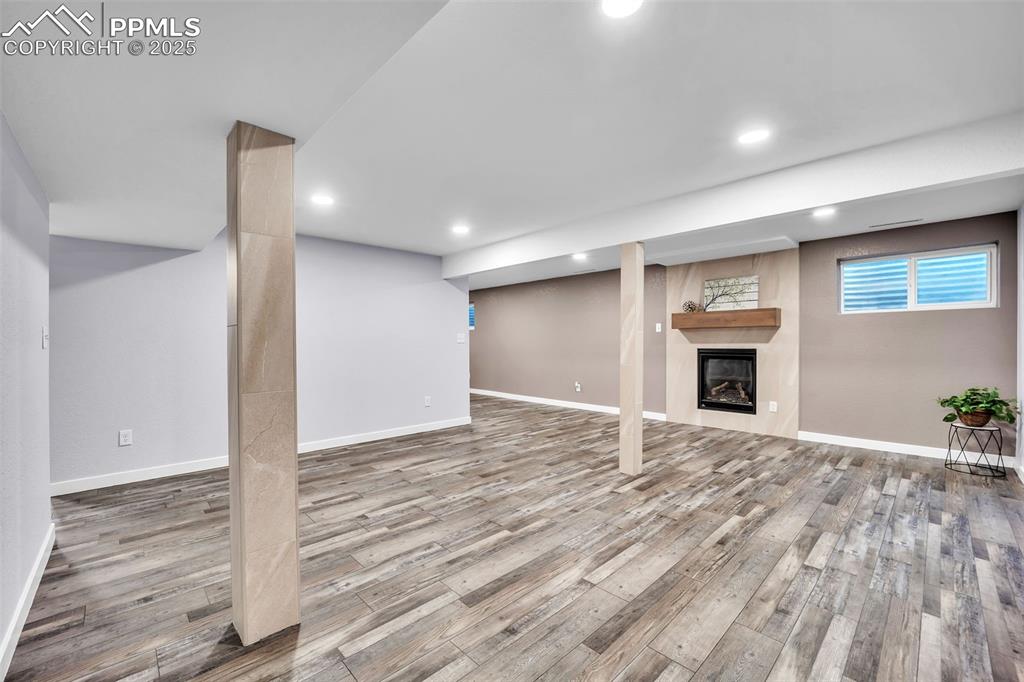 Image 30 of 49: Below grade area with a fireplace, recessed lighting, and light wood-type f