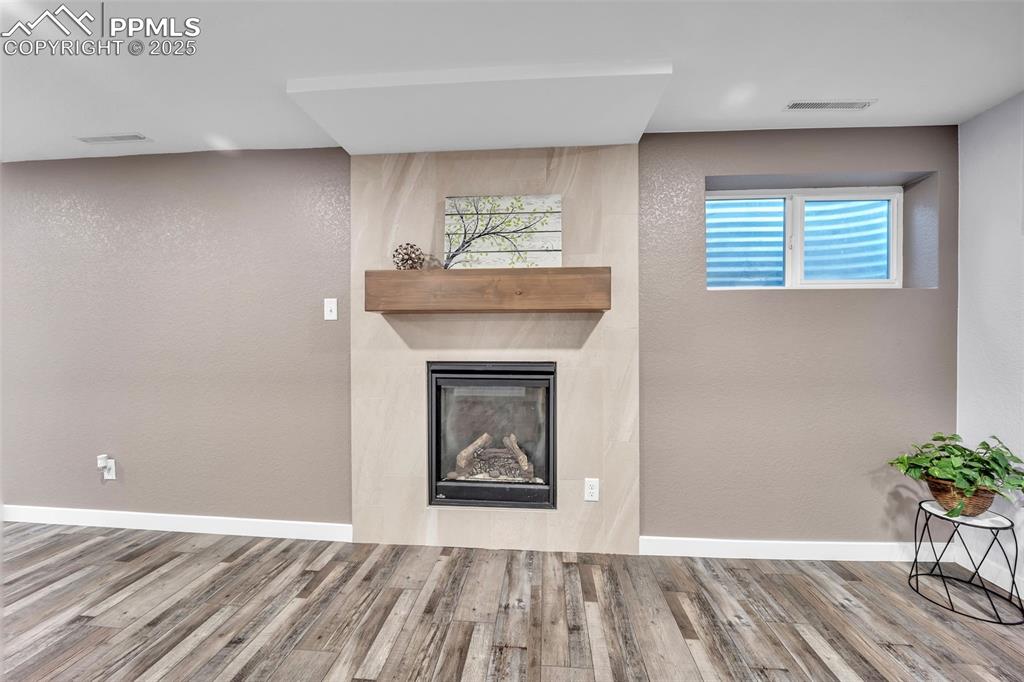 Image 31 of 49: Unfurnished living room with a glass covered fireplace, wood finished floor