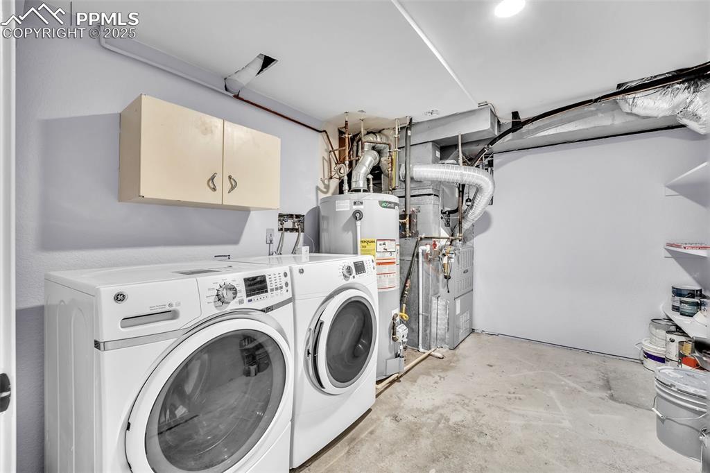 Image 38 of 49: Laundry room with water heater, independent washer and dryer, cabinet space