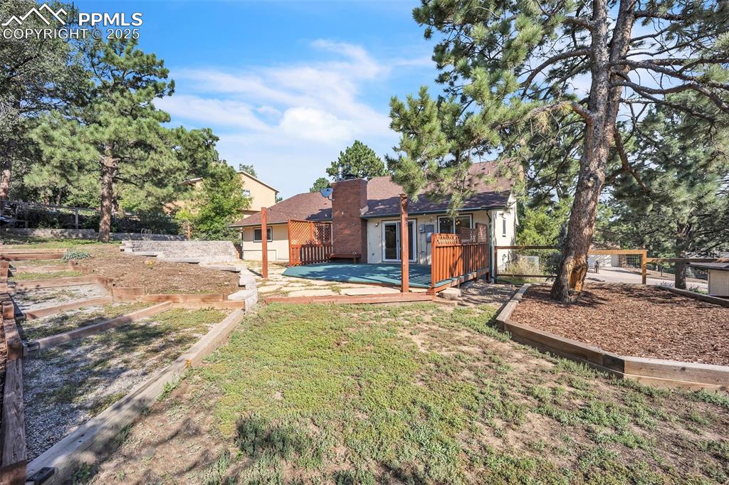 Image 42 of 49: Back of property featuring a deck, a chimney, a yard, and a patio area