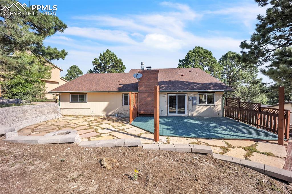 Image 43 of 49: Rear view of house featuring a chimney, roof with shingles, and a patio are