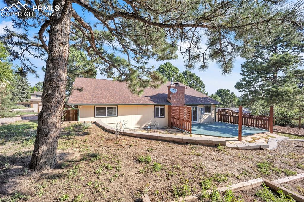 Image 44 of 49: Back of property with a wooden deck, roof with shingles, and a chimney