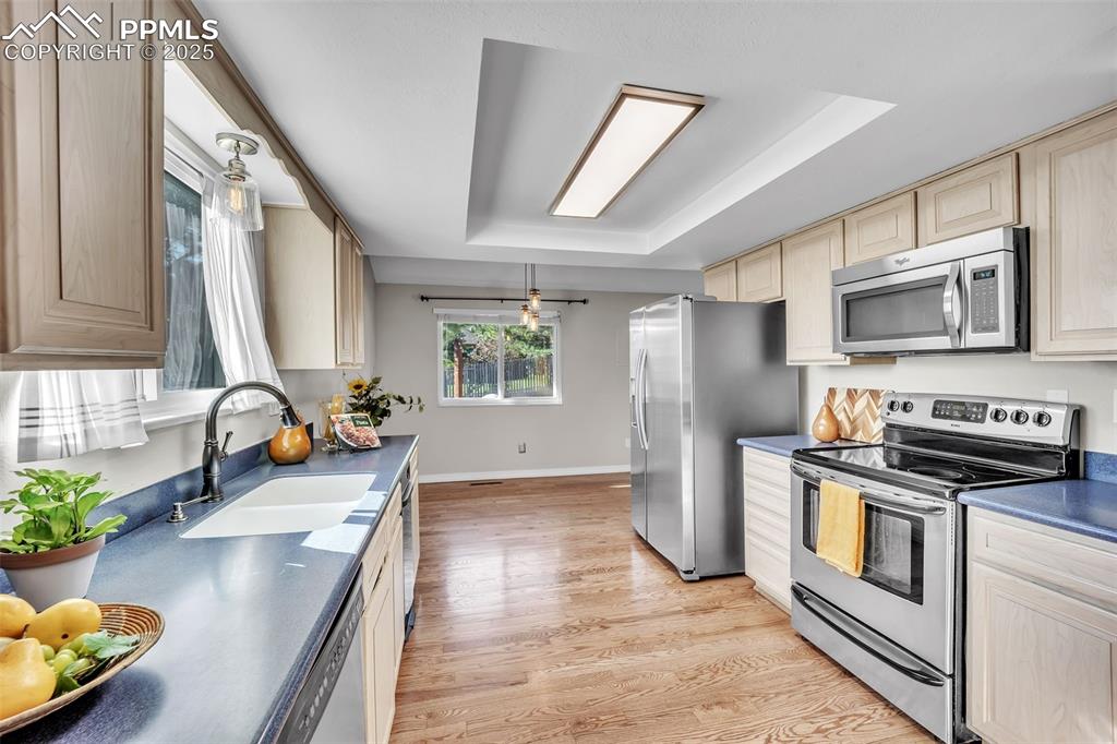 Image 7 of 49: Kitchen with appliances with stainless steel finishes, light wood finished
