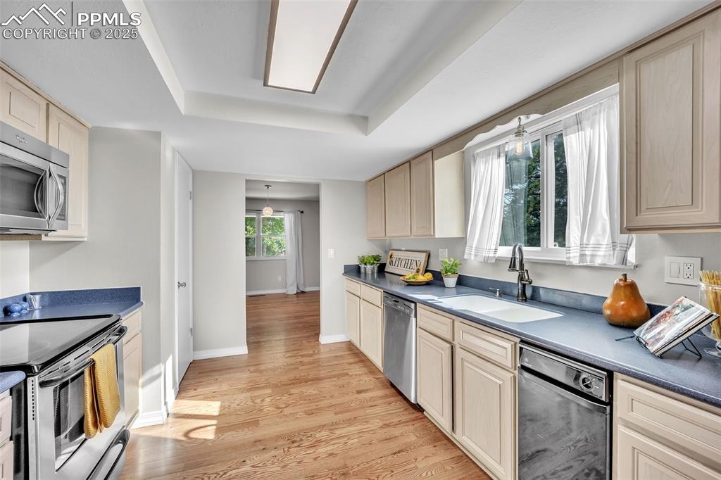 Image 9 of 49: Kitchen featuring dark countertops, stainless steel appliances, light wood-