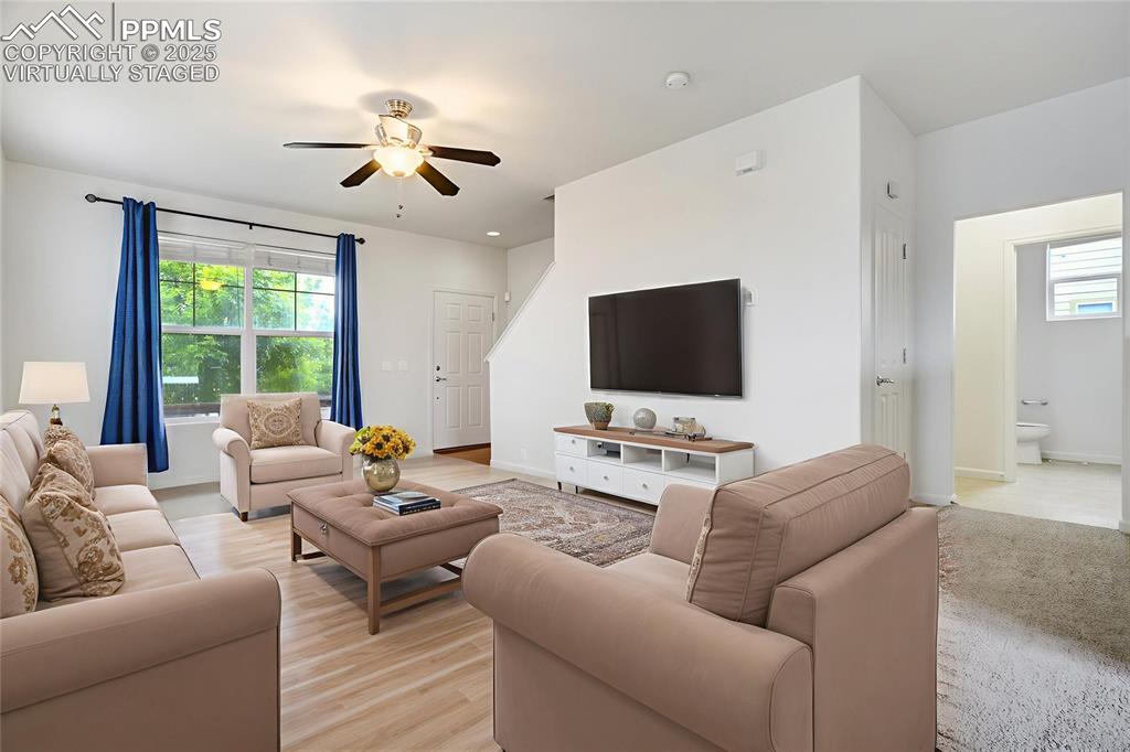 Image 10 of 50: Virtually staged living room toward front door with half bath on main