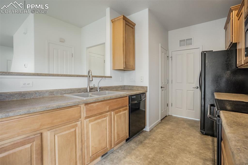 Image 22 of 50: Kitchen with dishwasher, a sink, stove, light brown cabinets with laundry a