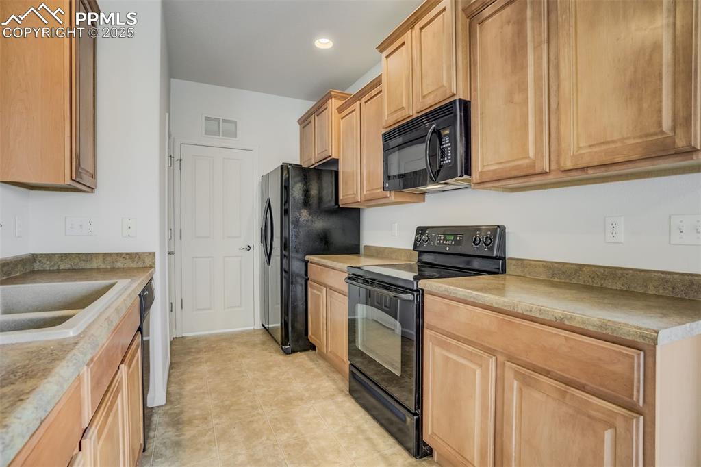 Image 23 of 50: Kitchen featuring black appliances, a sink, recessed lighting, and light br