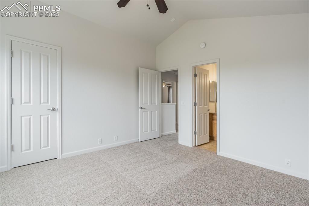 Image 29 of 50: Unfurnished primary bedroom featuring light colored carpet, lofted ceiling,