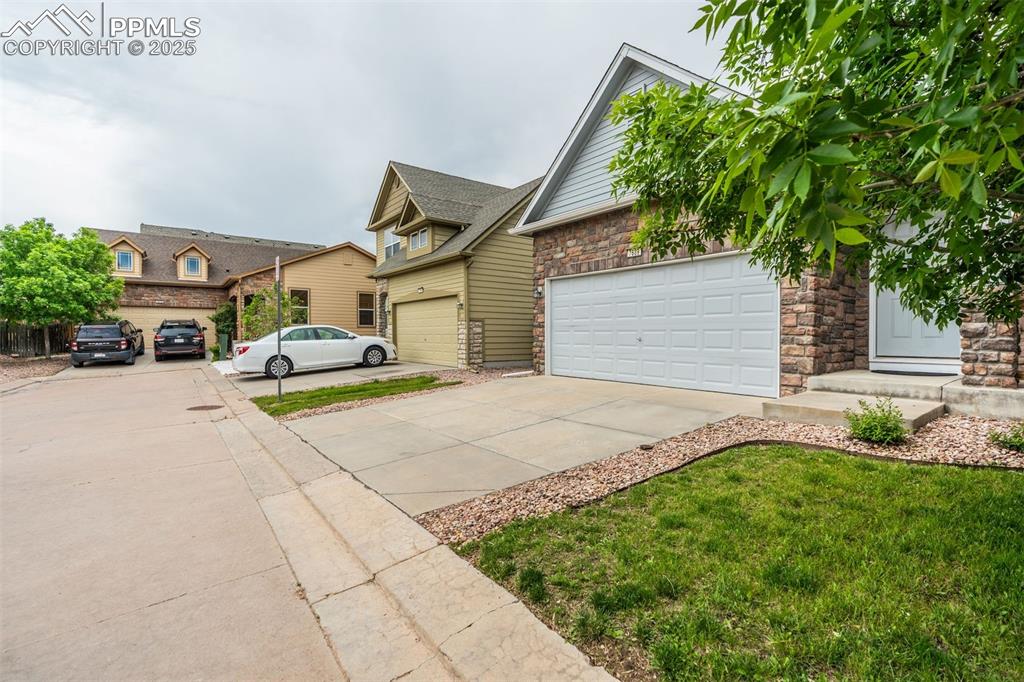 Image 3 of 50: View of front facade featuring concrete driveway, a garage, and stone sidin